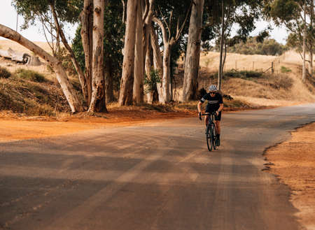 Athlete taking a break from cycling on an empty country roadの写真素材