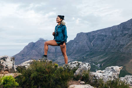 Concentrated woman in sportswear climbing up on the mountain looking away