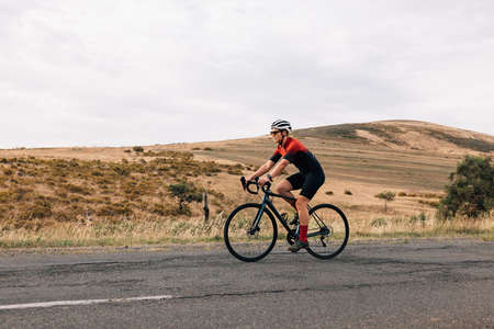 Woman riding bicycle on empty road. Cyclist rides her bike through empty countryside highway.の写真素材