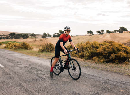 Professional female cyclist in sunglasses and helmet riding bike outdoorsの写真素材