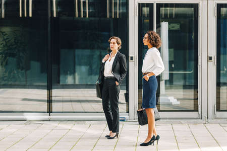 Young businesswoman discussing with her colleague while walking down the stairs near an office buildingの写真素材
