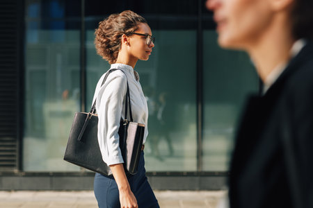 Two women commuting to the office in the day carrying office bags. Ceo and her assistant walking on a city street.の写真素材
