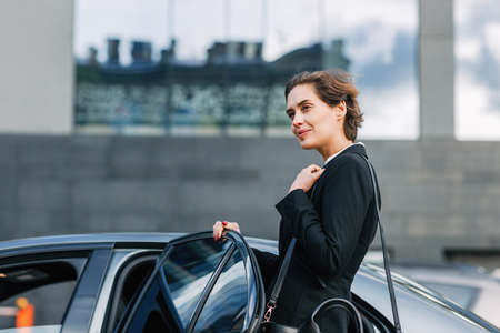 Businesswoman opening a door and entering a taxiの写真素材