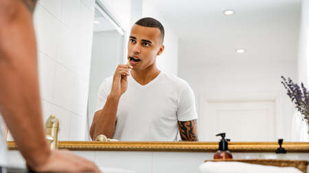 Bare-chested man checking out his skin in the bathroom mirror