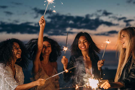 Smiling female friends holding instant photographs outdoorsの写真素材