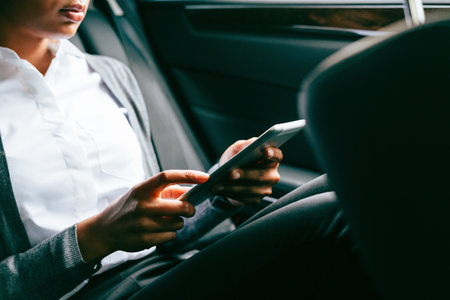 Unrecognizable woman using digital tablet, sitting on back seat of a carの写真素材