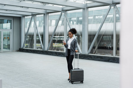 Young woman with luggage and cell phone preparing for business tripの写真素材