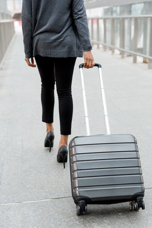 Unrecognizable businesswoman pulling suitcase inside of airport terminalの写真素材