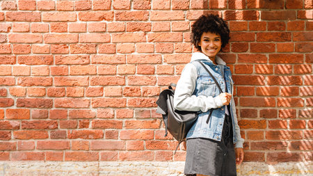 Smiling teenage girl standing at brick wallの写真素材