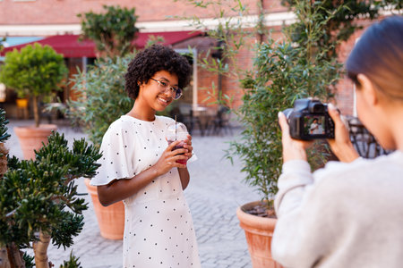 Young blogger with her personal photographer. Woman shooting client outdoors.の写真素材