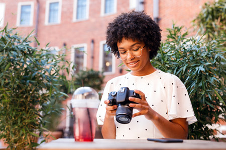 Young woman looking at digital camera while standing outdoors