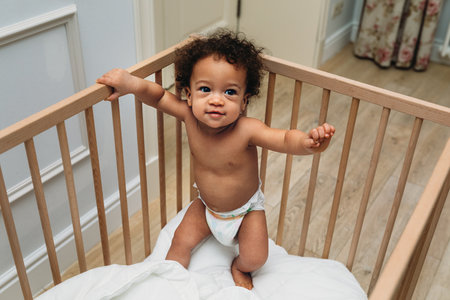 Curly haired toddler wearing a diaper in a cribの写真素材