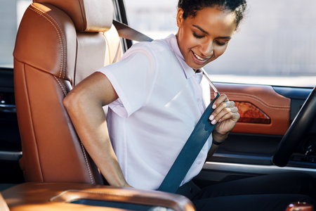 Young businesswoman fastening her seat belt in a carの写真素材