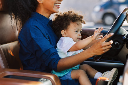 Smiling woman playing with son in a car holding the steering wheelの写真素材