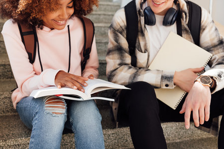 Cropped shot of two classmates sitting on stairs preparing assignments and smilingの写真素材