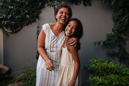 Portrait of granny and granddaughter embracing and laughing. Happy grandmother and kid standing...