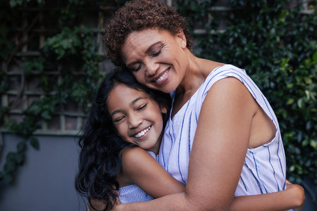 Granny and kid hugging. Happy grandma and granddaughter embracing with closed eyes at backyard.の写真素材