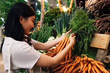 Woman buying carrot on the farmers market. Young female holding a bunch of carrots.の写真素材