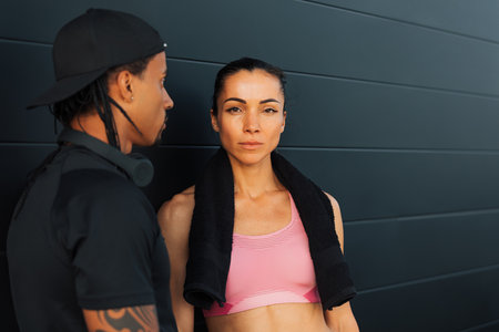 Portrait of a young female athlete at a black wall. Couple relaxing after workout.の写真素材