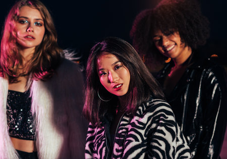 Close up portrait of Asian girl looking at camera. Portrait of three stylish women standing together at night.の写真素材