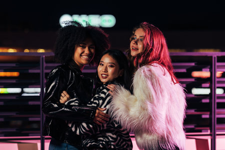 Smiling girls standing together outdoors at night and having funの写真素材