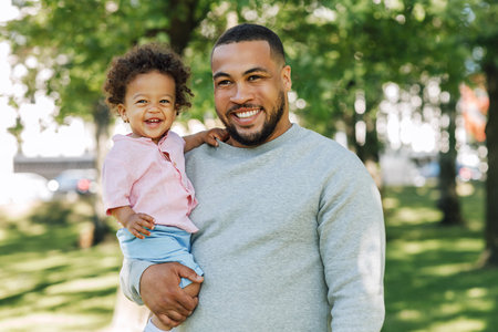 Young father holding son on hands. Happy little boy and his father in the park.の写真素材