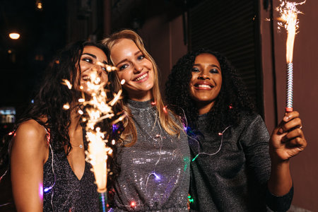 Young girls walking outdoors with sparklers and christmas lights around their bodiesの写真素材