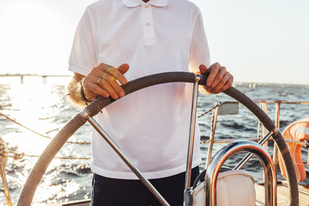 Unrecognizable man standing on a yacht and holding a steering wheelの写真素材
