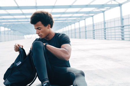 Male runner sitting on a road, looking at cameraの写真素材