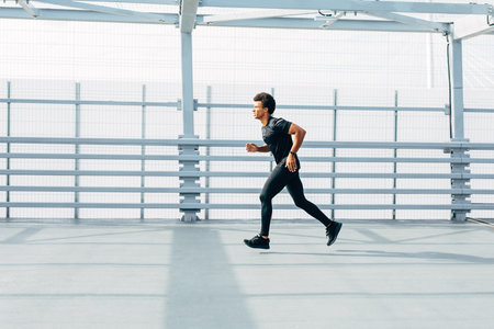 Side view of athlete sprinting in pedestrian tunnel. Male runner jogging at day.の写真素材