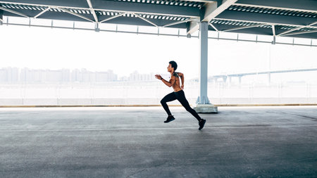 Side view of man sprinting under a bridgeの写真素材