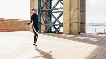 Female athlete skipping with jumping rope outdoors