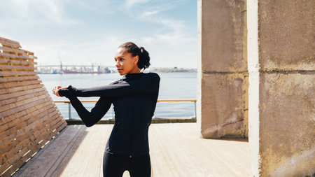 Woman in sportswear warming up hand before training at embankmentの写真素材
