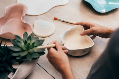 Hands of ceramist painting a bowl in studioの写真素材