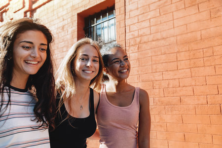 Three cheerful women walking together on city streetの写真素材