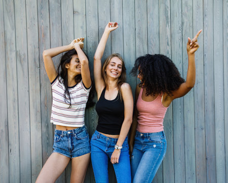 Three best friends dancing and enjoying on city street, raised hands upの写真素材