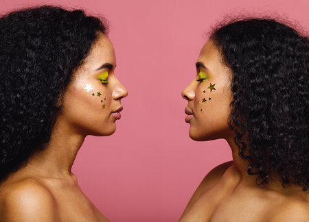 Side view of a two young women standing face to face with her eyes closedの写真素材
