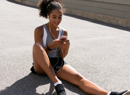 Athlete listening music while sitting on roadの写真素材