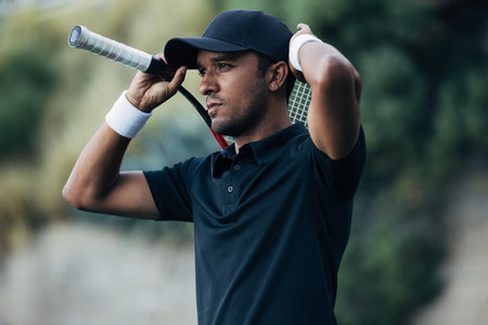 Young tennis player adjusting his cap during a matchの写真素材