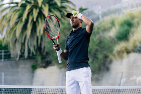 Young man with a tennis racket and tennis ball relaxing during a matchの写真素材