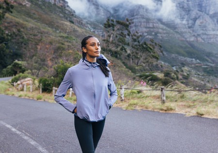 Young slim female in sportswear enjoying the view while walking. Woman doing morning walk in a...