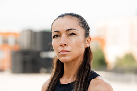Close-up portrait of a young sportswoman with long hair looking at cameraの写真素材