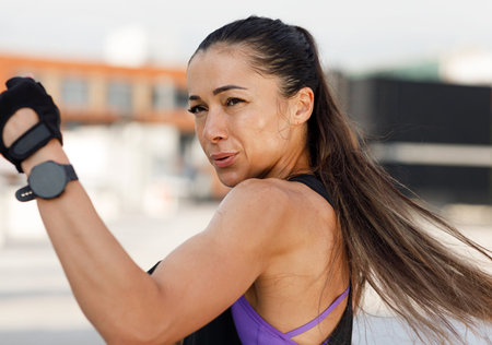 Woman doing high-intense warming up. High detailed portrait of a muscular athlete practicing punches outdoors.の写真素材