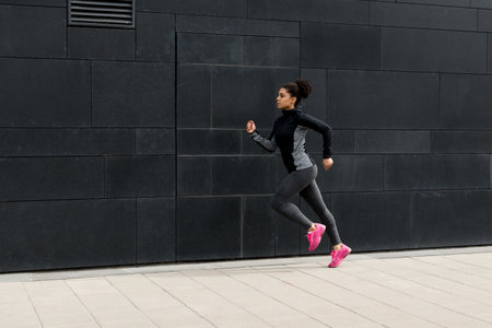 Side view of female athlete running near a wallの写真素材