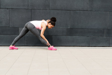 Young female runner warming up her body before training