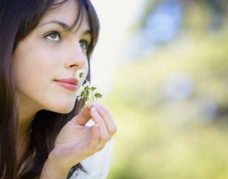 A young attractive Caucasian girl in white sweater smiling with daisies in her hand. の写真素材