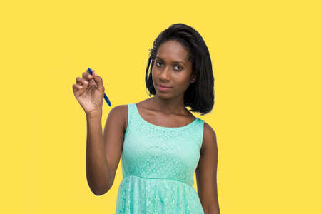 Woman writing with pen looking at cameraの写真素材