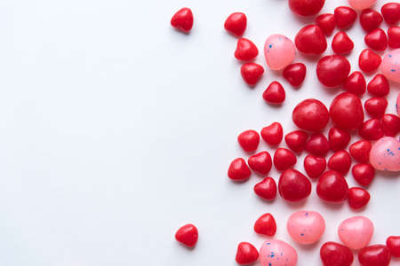 Scattered Valentine's Day cinnamon heart candies with red and pink jelly beans on white backgroundの写真素材