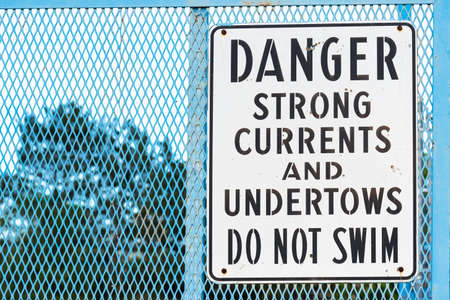 Sign by river warning of strong currents and undertows no swimmingの写真素材