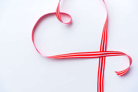 Flat lay arrangement of red and white striped in heart shape on white background